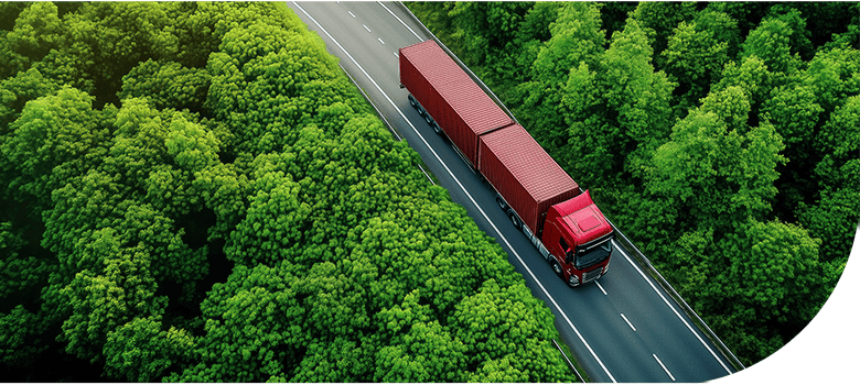A red freight truck driving along a forested road in the UK.